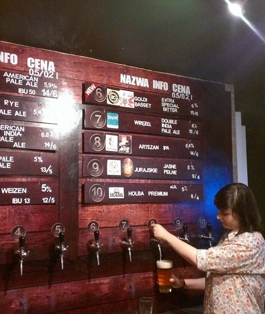 red wooden pub bar in warsaw with woman pulling pint of beer
